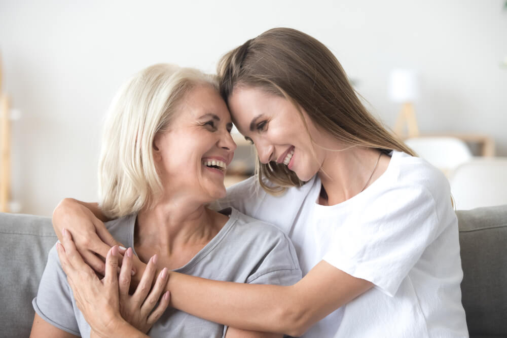 Seniorin und Tochter umarmen sich glücklich