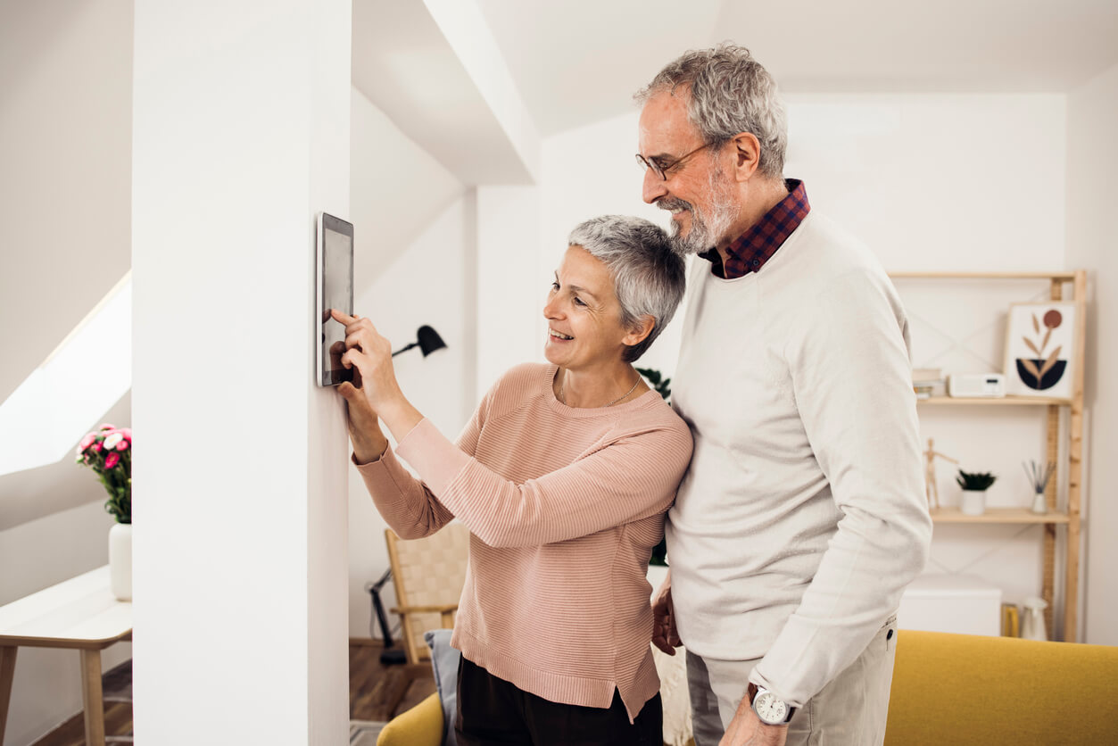 Eine Frau erklärt ihrem Ehemann eine Smart Home Steuerung